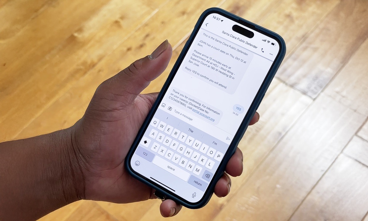 A hand holding a smartphone displaying a text message court date reminder.